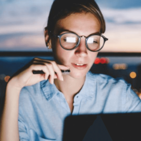 woman working on laptop with coastal sunset in background